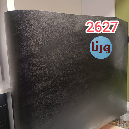 رول باز شده برچسب کابینت طرح چرم مشکی درشت بافت روی میز کار چوبی در کنار ابزار برش کاتر و خطکش