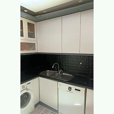 نصب برچسب مشکی طرح سنگ با رگه های طلایی روی دیوار بین کابینتی